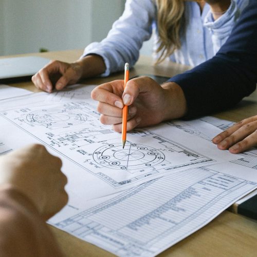 Team working on engineering plans, discussing ideas at an office meeting.